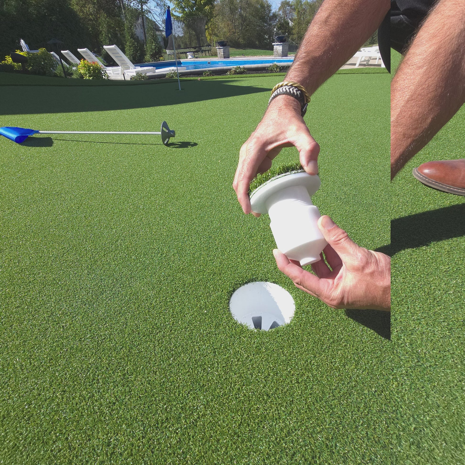 Video of someone holding a golf cup insert and showing how to adjust the height and set it in a golf cup on top of an artificial putting green. 