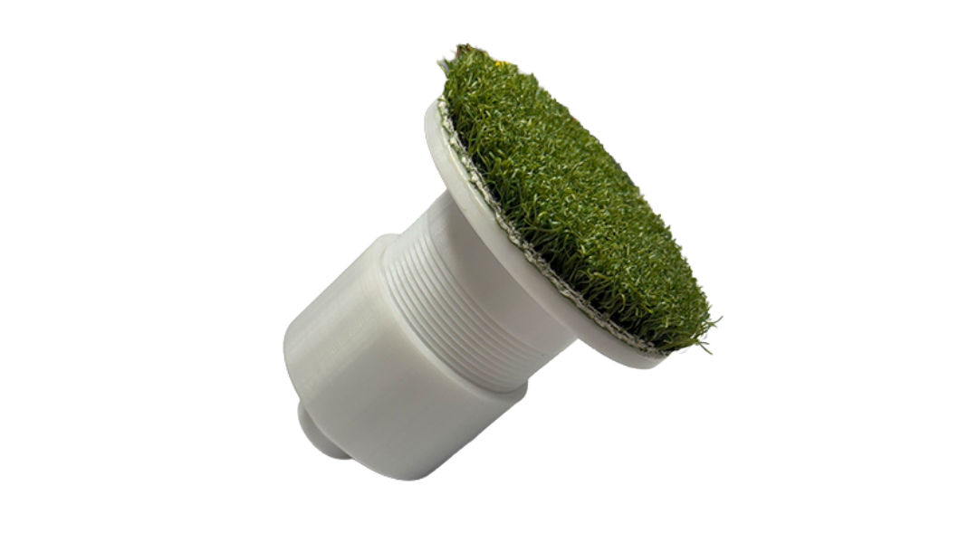 White plumbing fitting with green grass-like material on a white background